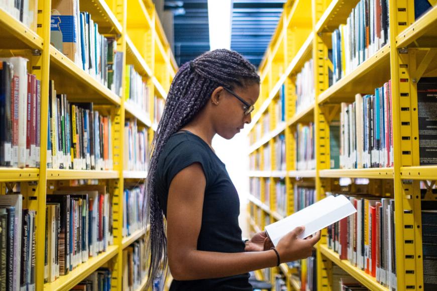 student in library holding book